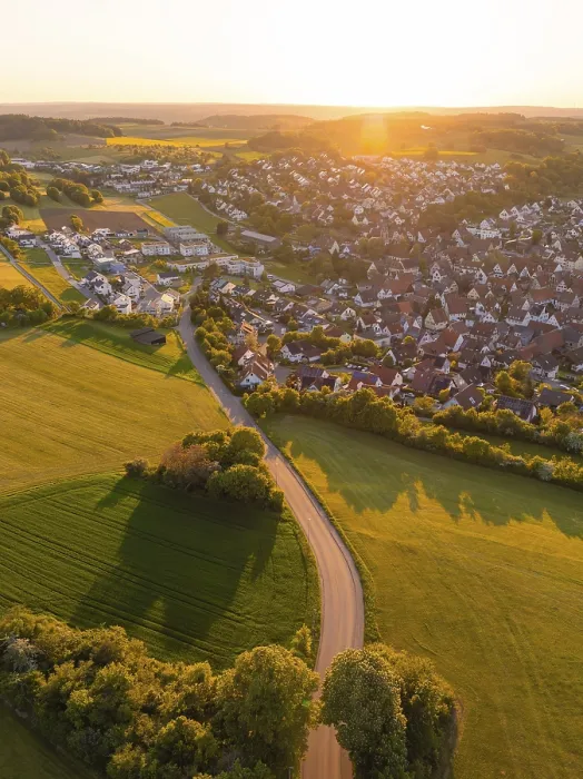 Framed Print : View of a village and a road surrounded by fields and trees at sunset