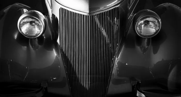 Framed Print : Front view of a vintage car in black and white with prominent headlights and grille in St