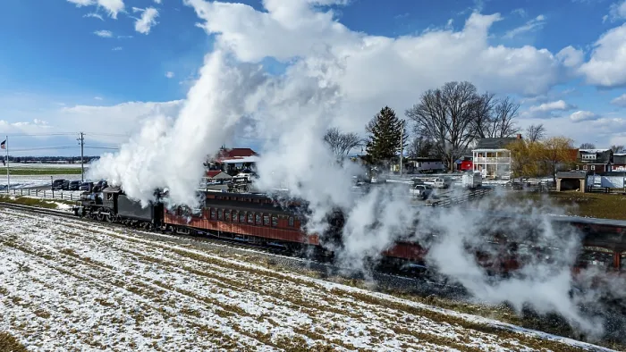 Framed Print : A vintage steam train moves through a landscape of snow-dusted fields under a clear blue sky