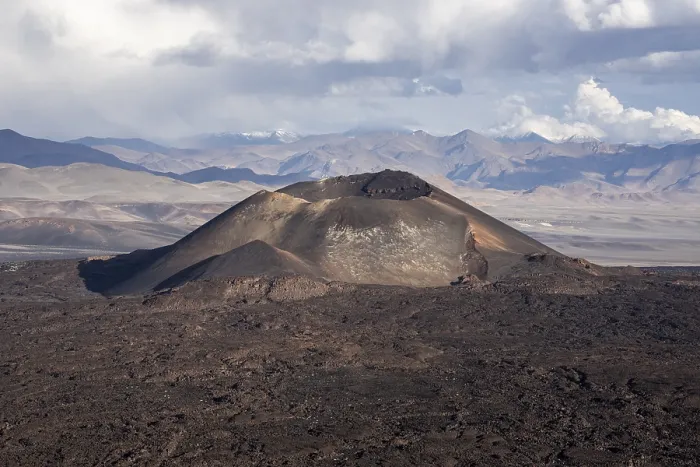Framed Print : A volcano rises in a vast rocky landscape under a cloudy sky Framed Print : A volcano rises in a vast rocky landscape under a cloudy sky