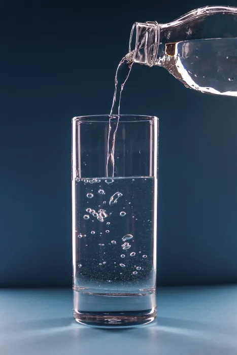 Framed Print : Water pours from a bottle into a glass on a blue background