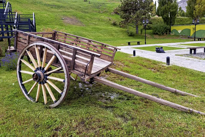 Framed Print : Weathered carriage on a green surface surrounded by hills and trees