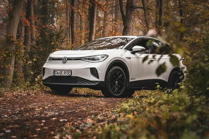 Framed Print : White car parked in forest surrounded by autumn leaves