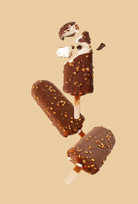 Framed Print : White popsicle in chocolate glaze with nuts flying on a beige background Framed Print : White popsicle in chocolate glaze with nuts flying on a beige background