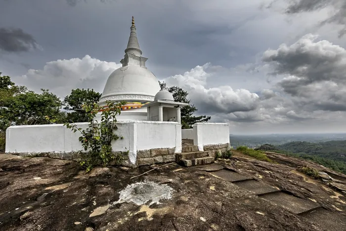 Framed Print : White stupa on rocky hill surrounded by cloudy skies and lush nature