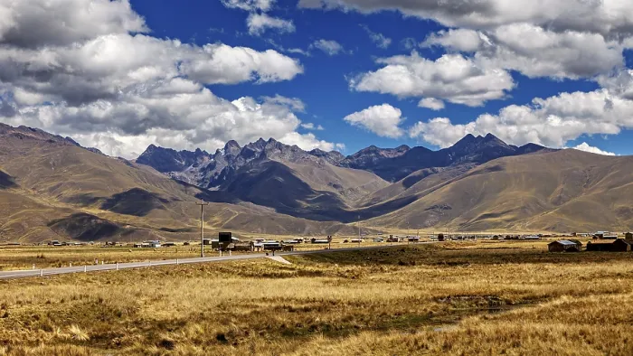 Framed Print : Wide landscape with a road between rolling mountains under a blue sky with clouds