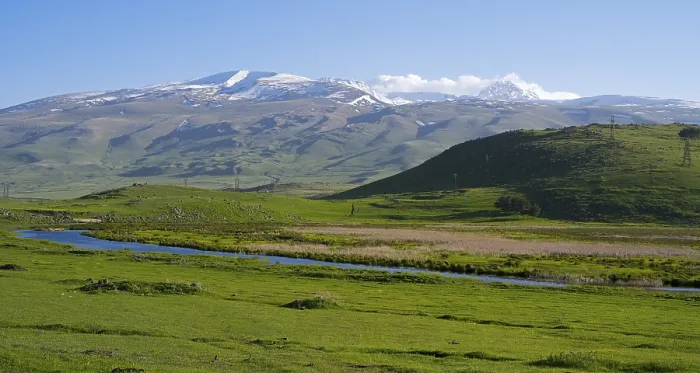 Framed Print : A wide view over a green valley with snow-capped mountains under a clear sky