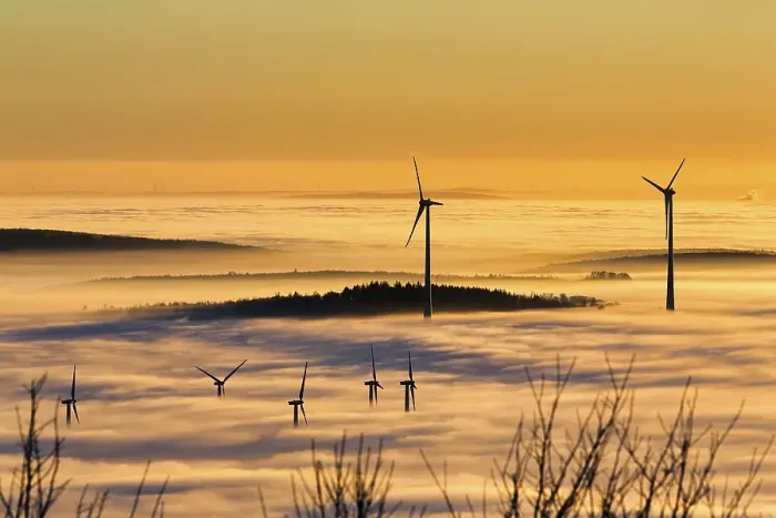 Framed Print : Wind turbines and forest rising from cloud cover
