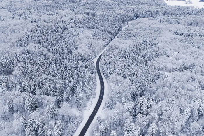 Framed Print : Winding road through snowy winter forest from the air