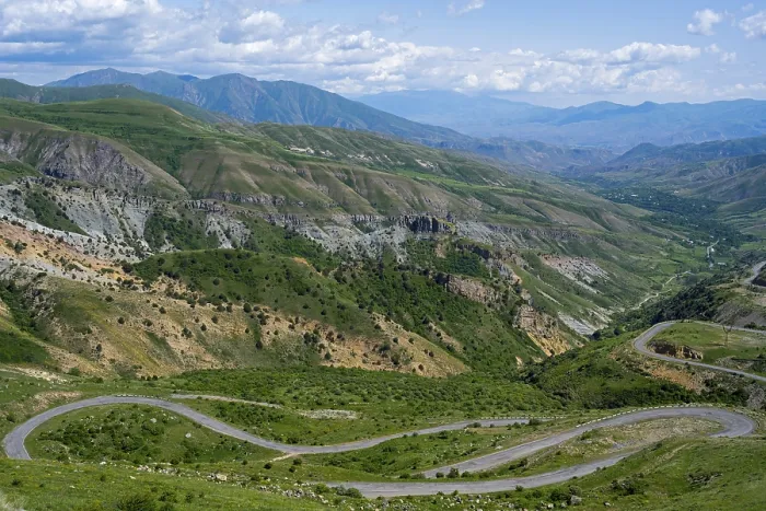 Framed Print : A winding road winds through the green mountains under a blue sky