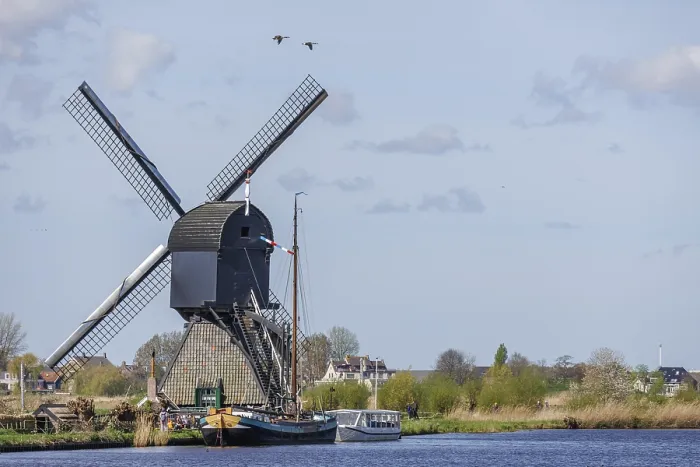 Framed Print : Windmill on the river bank with boats and grasses in the foreground