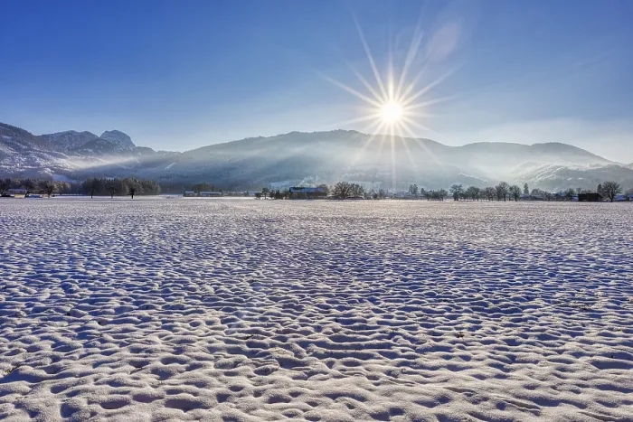 Framed Print : Winter landscape with snow-covered field and rising sun against a mountain backdrop Framed Print : Winter landscape with snow-covered field and rising sun against a mountain backdrop