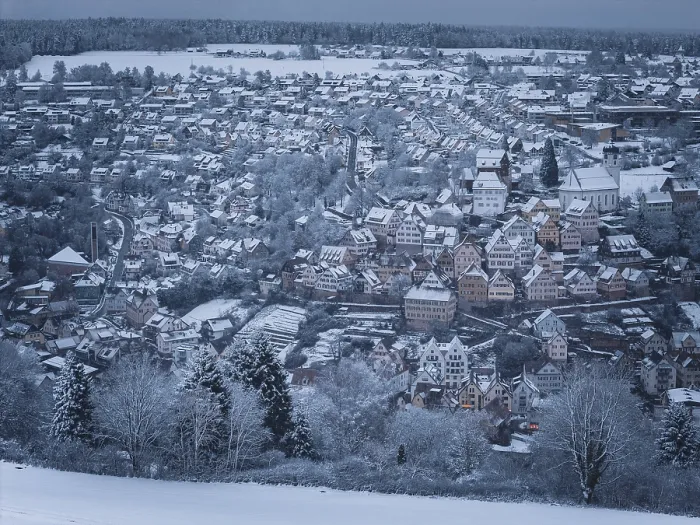 Framed Print : Wintery city view with snow-covered half-timbered houses and surrounding trees