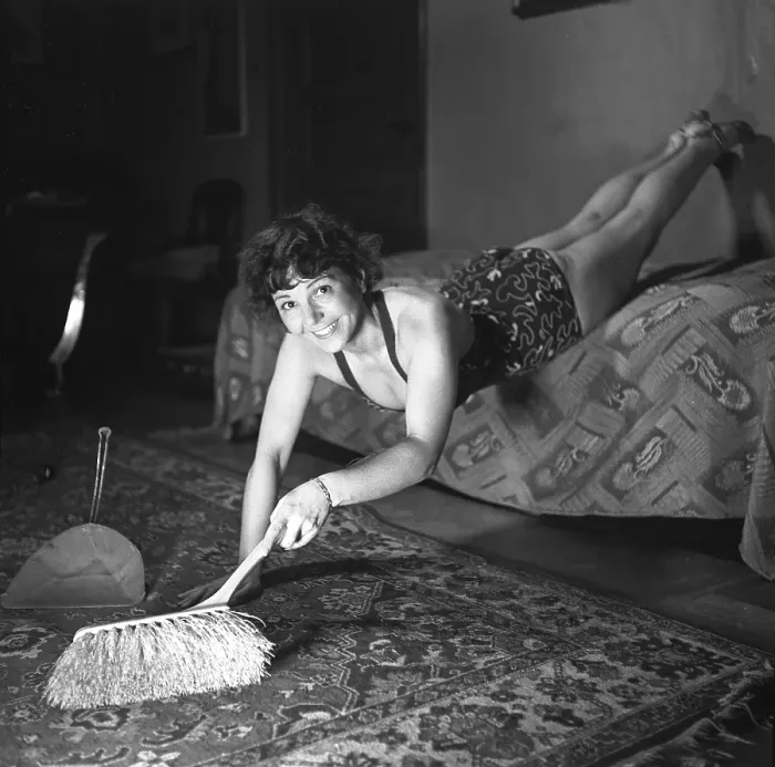 Framed Print : Woman of the 1940s. A woman is seen practising gymnastics while cleaning and dusting