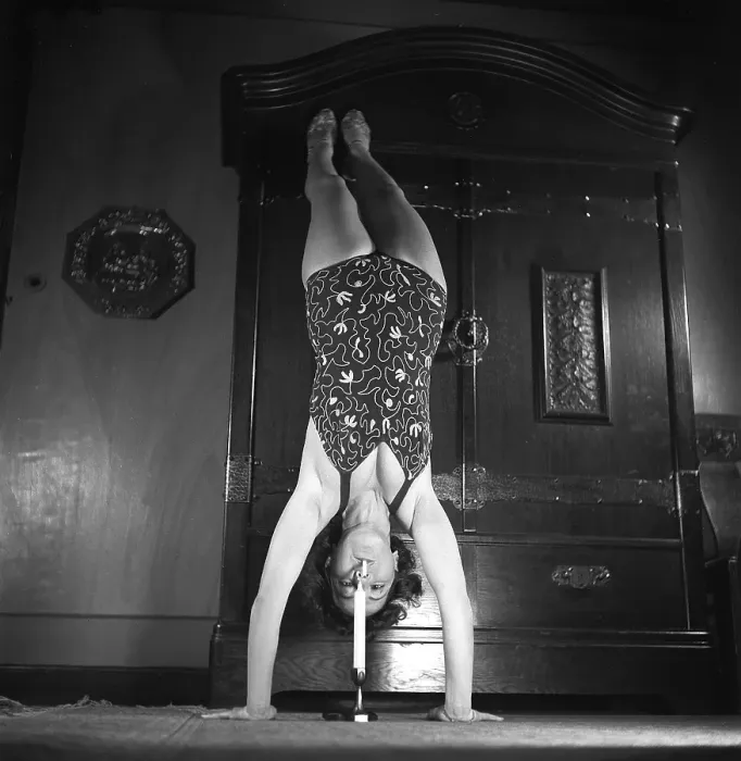 Framed Print : Woman of the 1940s. A woman is seen practising gymnastics while lighting her cigarette on a candle