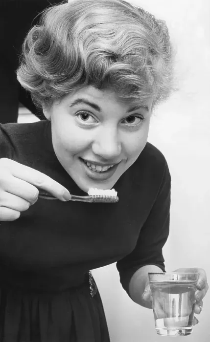 Framed Print : Woman in the 1950s. A young woman is brushing her teath Framed Print : Woman in the 1950s. A young woman is brushing her teath