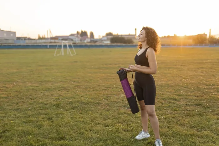 Framed Print : Woman with curly hair smiles while holding a yoga mat on a field