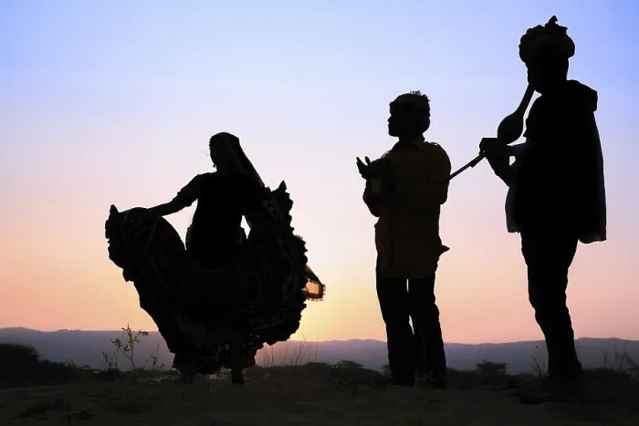 Framed Print : Woman dancing in front of the setting sun with two musicians