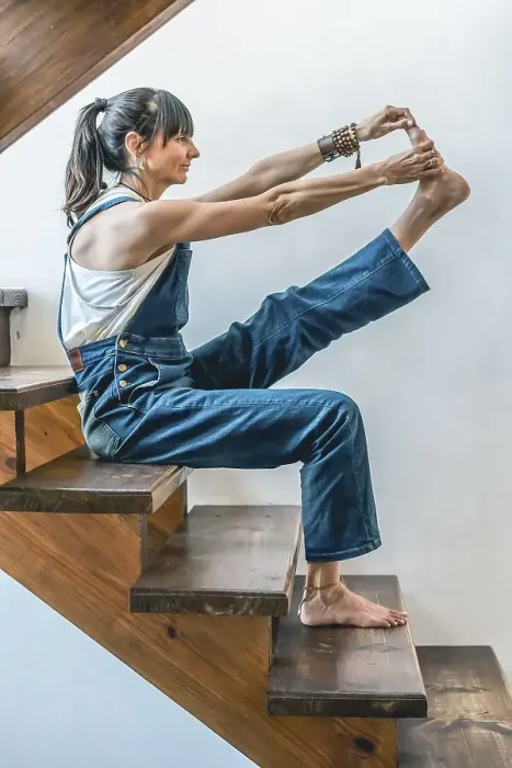 Framed Print : A woman doing stretching exercises on the stairs of her home