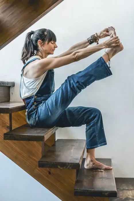 Framed Print : A woman doing stretching exercises on the stairs of her home