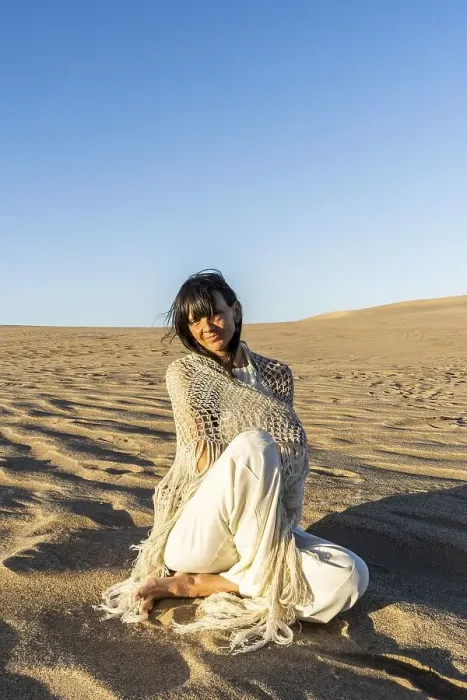 Framed Print : A woman dressed in white sitting on the sand at sunset