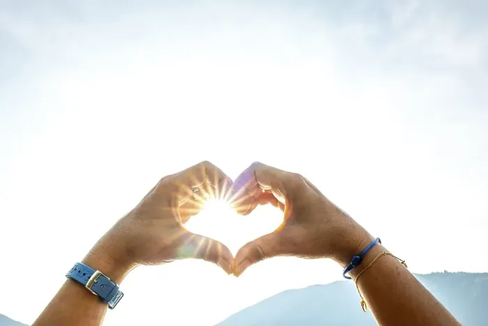 Framed Print : Woman Hands Making a Heart Shape Against the Sky with Sun and Sunbeam and Mountain in Switzerland