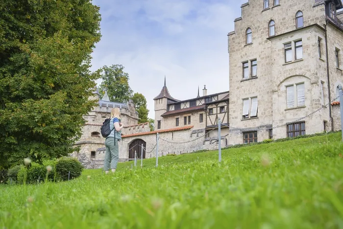 Framed Print : A woman next to a historic building with a green meadow and trees in the background Framed Print : A woman next to a historic building with a green meadow and trees in the background