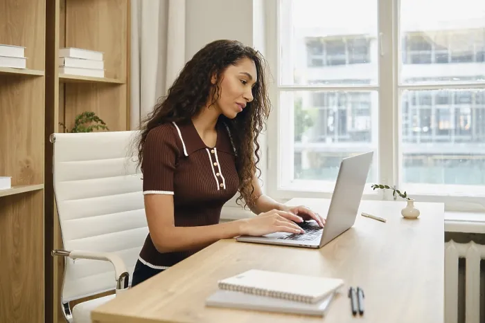 Framed Print : A woman with long curly hair is seated at a stylish wooden desk in a contemporary office Framed Print : A woman with long curly hair is seated at a stylish wooden desk in a contemporary office