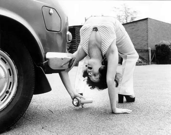 Framed Print : Woman looks under a car with flashlight Framed Print : Woman looks under a car with flashlight