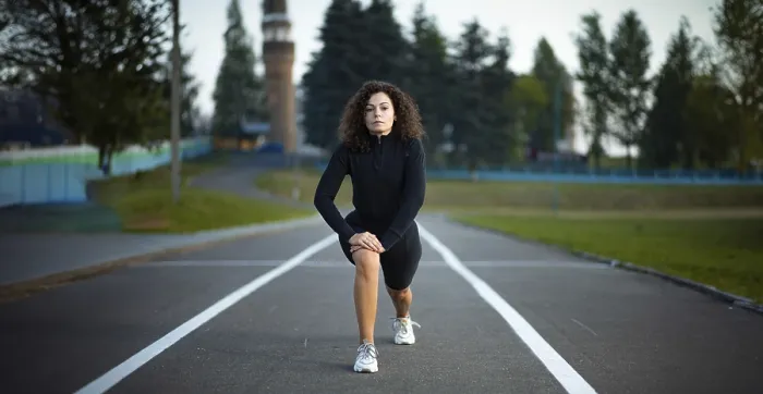 Framed Print : Woman performing a lunge exercise on a road with trees in the background