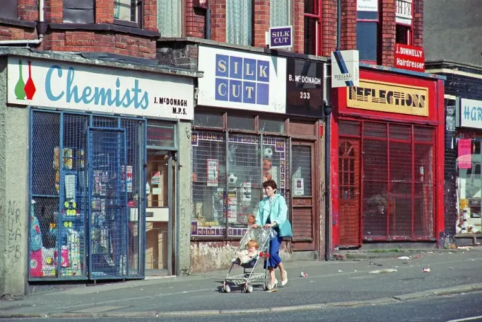 Framed Print : Woman with pram in front of barred shops