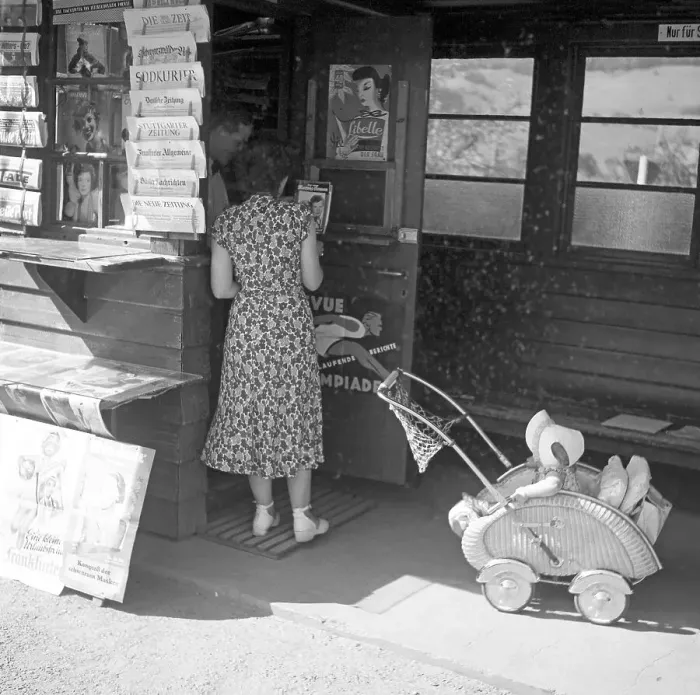 Framed Print : Woman with pram looks after newspapers