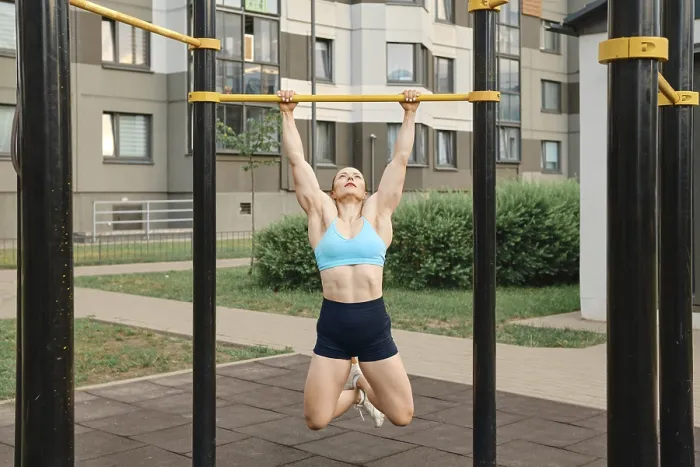 Framed Print : Woman pulls herself up on bar on sports field of residential area