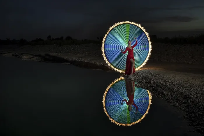 Framed Print : Woman in red dress, performs in elegant pose a colourful light painting with reflection at a lake Framed Print : Woman in red dress, performs in elegant pose a colourful light painting with reflection at a lake