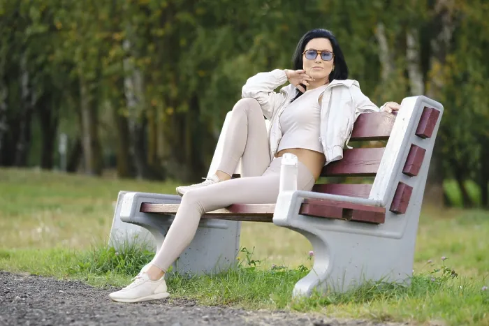 Framed Print : A woman sits on a park bench dressed in light-colored casual clothes