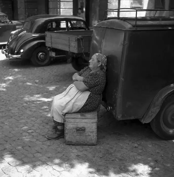 Framed Print : Woman sitting on a wooden box and leaning against a car