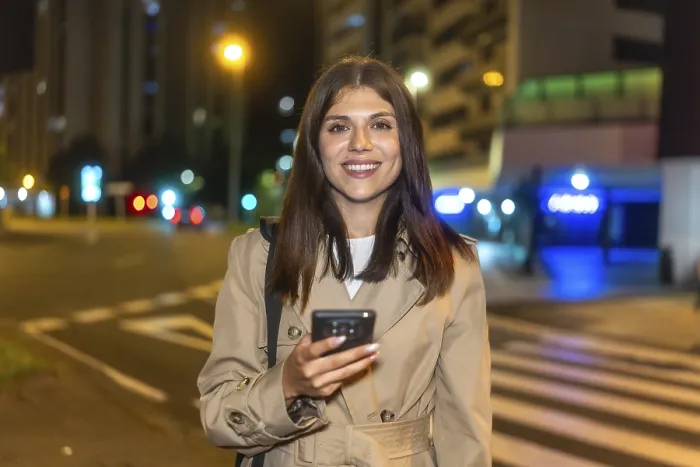 Framed Print : Woman smiling brightly and holding a smartphone