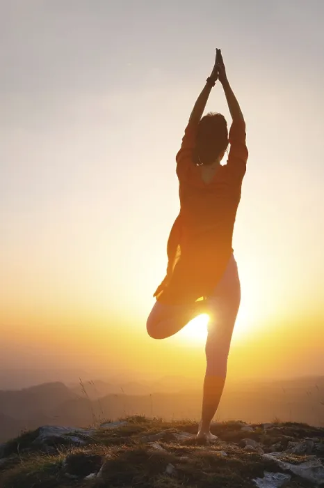 Framed Print : A woman stands in a yoga pose against the sun in the mountains