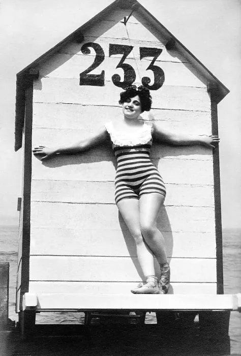 Framed Print : Woman in swimsuit posing in front of a historic dressing room on the beach