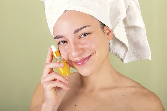 Framed Print : A woman with a towel wrapped around her head holds a small bottle of facial serum Framed Print : A woman with a towel wrapped around her head holds a small bottle of facial serum