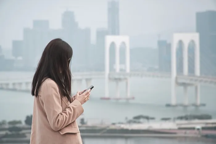 Framed Print : Woman, using phone with Sai Van Bridge in the background