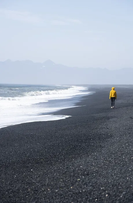 Framed Print : Woman walking on a black sand beach