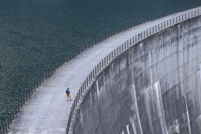 Framed Print : Woman, walking alone along a large dam with a view of the endless expanse of water Framed Print : Woman, walking alone along a large dam with a view of the endless expanse of water