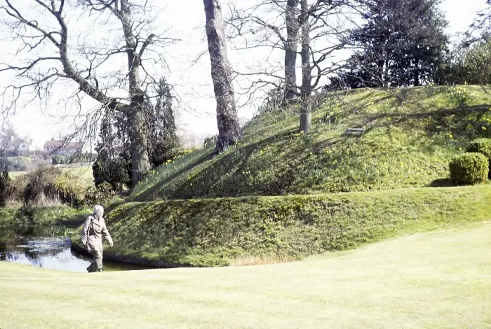 Framed Print : Woman walking past the hill of the Norman castle Motte and Bailey, Abinger, Surrey, England, UK 1980