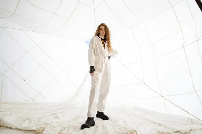 Framed Print : A woman in a white jumpsuit poses in front of a white netting background