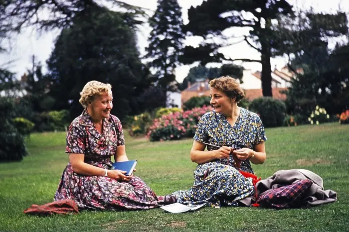 Framed Print : Two women friends sitting on grass lawn one knitting, smiling at each other, Dawlish, Devon, England, UK early 1960s