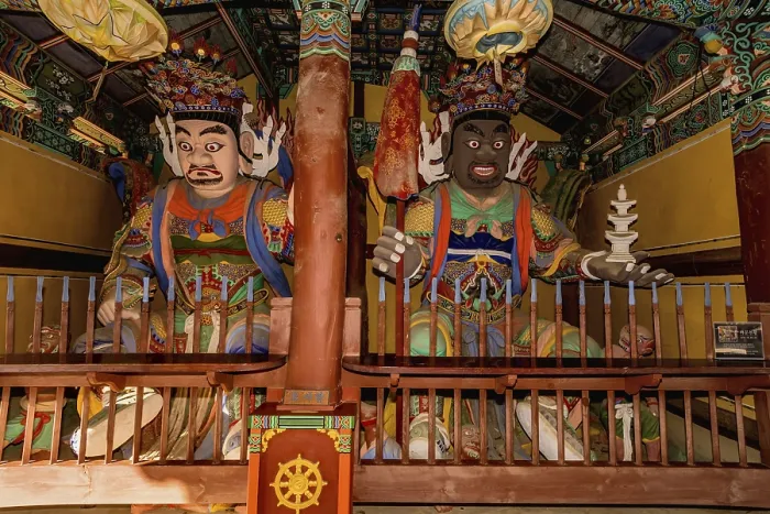 Framed Print : Wood carved statues of two Buddhist deities in covered pavilion at temple