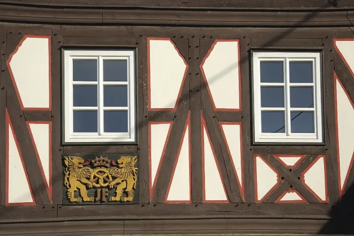 Framed Print : Wood carving with lion figures and pretzel on half-timbered house