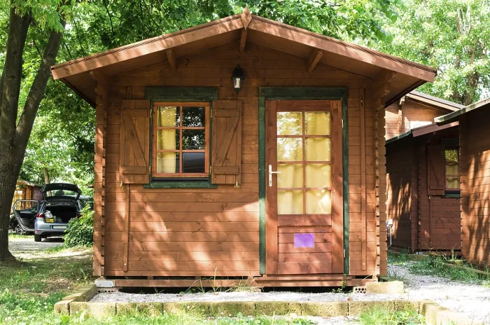 Framed Print : Wooden bungalows on campsite camping. Green trees