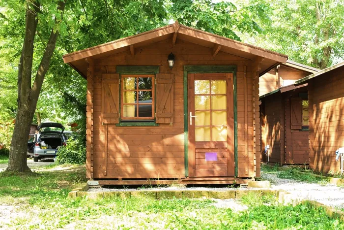 Framed Print : Wooden bungalows on campsite camping. Green trees